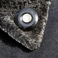 Le Bouton de Deuil en onyx avec le bouton d'un être cher est porté comme épingle de revers sur un epais manteau d'hiver.